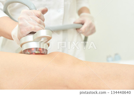 Female asian adult receiving professional knee treatment with advanced laser Female asian adult receiving professional knee treatment with advanced laser 134448640