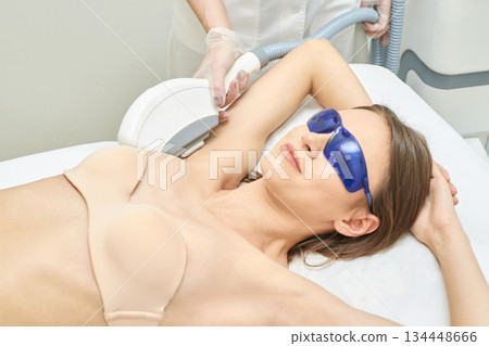 Young caucasian female undergoing laser hair removal treatment in clinic Young caucasian female undergoing laser hair removal treatment in clinic 134448666