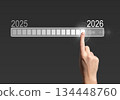 Loading bar progress. Female hand touching digital screen, symbol of 2025 to 2026 transition, 134448760