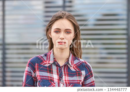 Young caucasian female in plaid shirt outdoors with blurred background 134448777