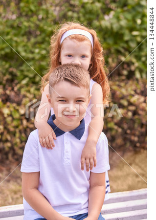Caucasian young boy and girl smiling in park setting, showing sibling bond 134448844