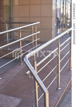 Accessible urban outdoor ramp with stainless steel handrails and concrete path Accessible urban outdoor ramp with stainless steel handrails and concrete path 134449010