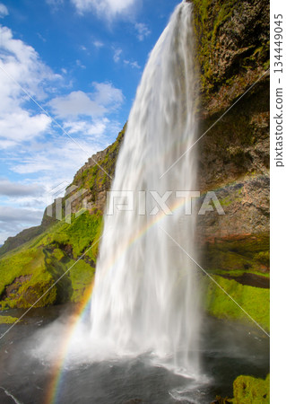 Seljalandsfoss waterfall, flowing down the Seljalandssá River in the Nordic island nation of Iceland, with a rainbow 134449045