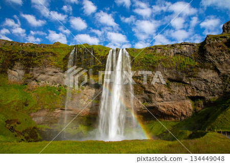 Seljalandsfoss waterfall, flowing down the Seljalandssá River in the Nordic island nation of Iceland, with a rainbow 134449048
