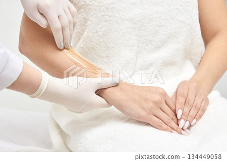 Female receiving arm waxing treatment in salon by caucasian professional 134449058