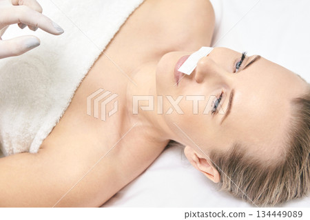 Caucasian female receiving lip wax treatment lying on bed close-up beauty spa Caucasian female receiving lip wax treatment lying on bed close-up beauty spa 134449089
