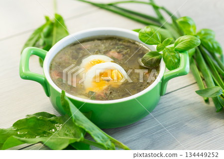 Top view of a plate of green borscht with egg and sorrel on light wooden table Top view of a plate of green borscht with egg and sorrel on light wooden table 134449252