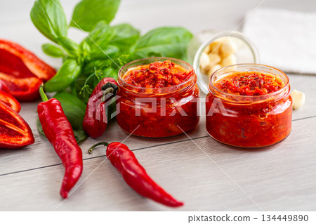 Delicious chili paste with garlic and basil on wooden surface 134449890
