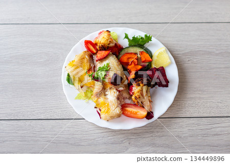 Oven baked fish fillet with vegetables and lemon garnish Oven baked fish fillet with vegetables and lemon garnish 134449896