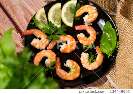 Boiled red shrimps with lemon on a wooden table Boiled red shrimps with lemon on a wooden table 134449905