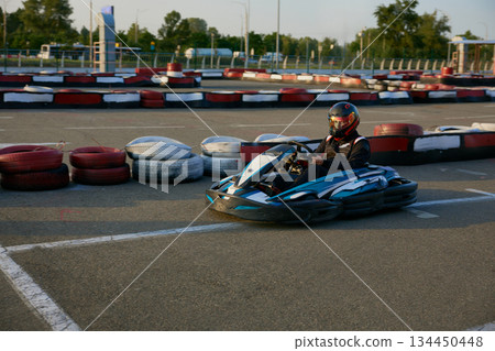 A thrilling go-kart professional racer speeds on an outdoor training track A thrilling go-kart professional racer speeds on an outdoor training track 134450448