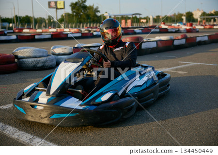 A thrilling go-kart racer speeds on an outdoor track A thrilling go-kart racer speeds on an outdoor track 134450449