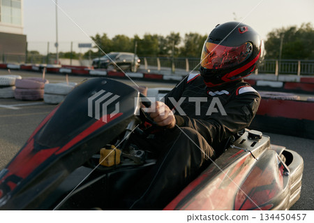 A passionate racer skillfully drives a gokart with great determination on an outdoor track A passionate racer skillfully drives a gokart with great determination on an outdoor track 134450457