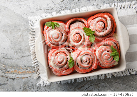 Freshly baked pink cinnabon buns with cream sauce in a baking dish. Horizontal top view 134450655