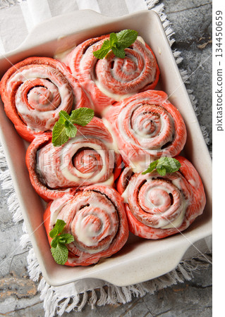 Close-up of pink cinnamon rolls with white icing in a baking dish. Vertical top view Close-up of pink cinnamon rolls with white icing in a baking dish. Vertical top view 134450659