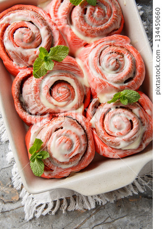 Freshly baked pink cinnabon buns with cream sauce  closeup on the baking dish on the table. Vertical top view 134450660