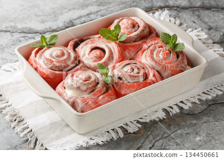 Freshly baked pink cinnabon buns with cream sauce in a baking dish. Horizontal 134450661