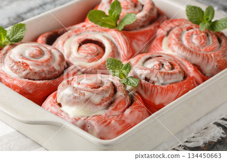 Festive pink cinnabons, cinnamon rolls with white icing, close-up in a baking pan. Horizontal 134450663