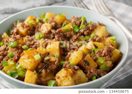 Fried potatoes with ground beef and green onions close-up in a plate. Horizontal 134450675