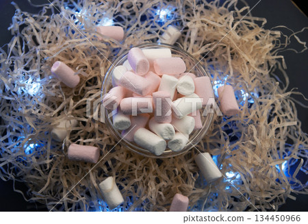 White and pink marshmallows in a transparent cup with a garland. White and pink marshmallows in a transparent cup with a garland. 134450966
