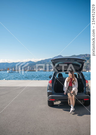 A young woman taking a break after parking near the sea under a blue sky 134452929