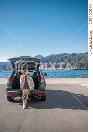A young woman taking a break after parking near the sea under a blue sky 134452930