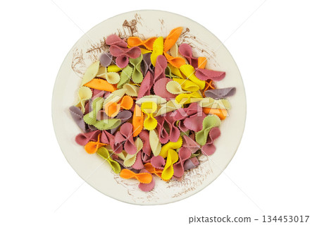 Farfalle on ceramic plate isolated on white background. Top view. Uncooked pasta of different colors. 134453017