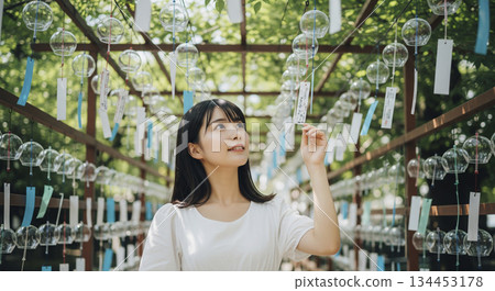 A woman standing under a pile of hanging wind chimes 134453178