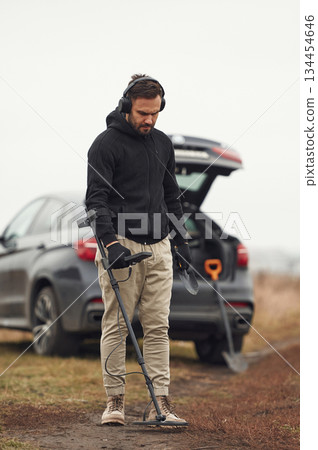 Against the car. Man is with metal detector in the field Against the car. Man is with metal detector in the field 134454646