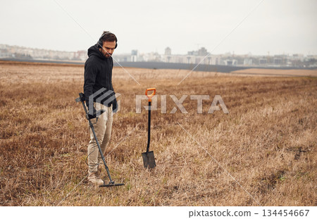 Archeology conception. Man is with metal detector in the field Archeology conception. Man is with metal detector in the field 134454667