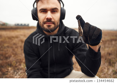 Man sapper in headphones is holding old bullet that he found in the field Man sapper in headphones is holding old bullet that he found in the field 134454682