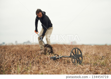 Digging the hole. Man is with metal detector in the field Digging the hole. Man is with metal detector in the field 134454719
