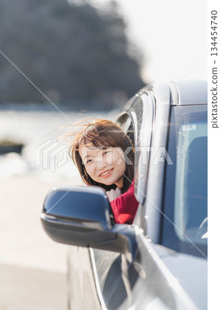 一位身穿紅色針織衫的年輕女子在汽車座椅上向前傾身。 134454740