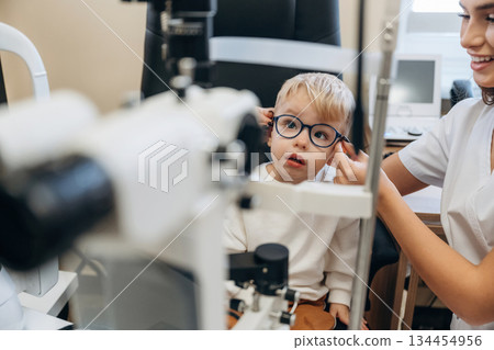 In the new glasses. Little boy is having check up in the ophthalmologist cabinet In the new glasses. Little boy is having check up in the ophthalmologist cabinet 134454956