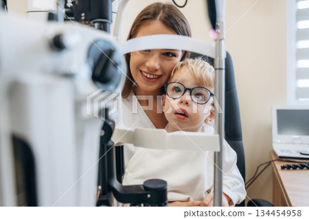 In the new glasses. Little boy is having check up in the ophthalmologist cabinet 134454958