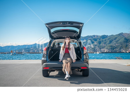 在陽光明媚的日子裡,一位年輕女子開車前往海邊。 在陽光明媚的日子裡,一位年輕女子開車前往海邊。 134455028