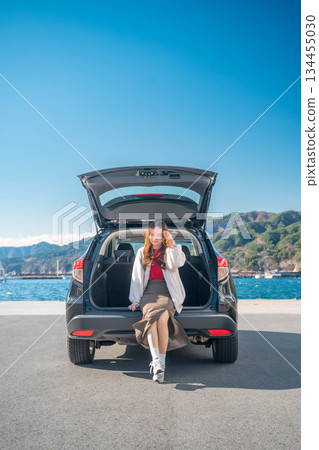 在陽光明媚的日子裡,一位年輕女子開車前往海邊。 在陽光明媚的日子裡,一位年輕女子開車前往海邊。 134455030