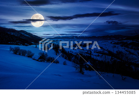 winter in mountainous countryside at night. gorgeous cloudy sky over the snow covered hills in full moon light. wide mountain ridge in a far distance. backdrop for fiction art or mystery concepts winter in mountainous countryside at night. gorgeous cloudy sky over the snow covered hills in full moon light. wide mountain ridge in a far distance. backdrop for fiction art or mystery concepts 134455085