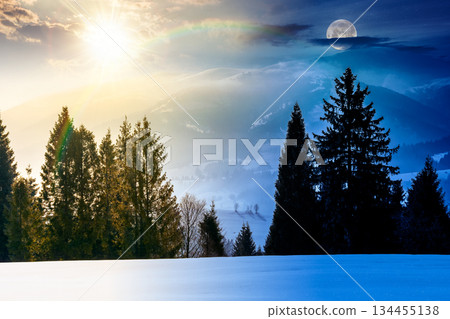 winter solstice landscape. day and night time change concept. fir trees on snow covered hill with sun and moon. place in mountains. winter wonderland background for harmony and progress calendar 134455138
