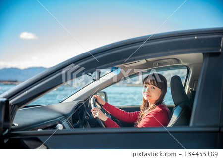 A young long-haired woman driving a car on a sunny day A young long-haired woman driving a car on a sunny day 134455189