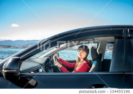A young long-haired woman driving a car on a sunny day A young long-haired woman driving a car on a sunny day 134455190