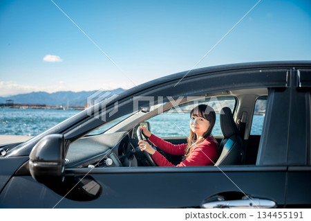 A young long-haired woman driving a car on a sunny day A young long-haired woman driving a car on a sunny day 134455191