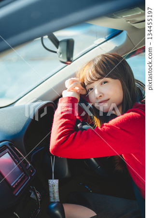 在陽光明媚的日子裡,一位留著長髮的年輕女子開車。 在陽光明媚的日子裡,一位留著長髮的年輕女子開車。 134455197