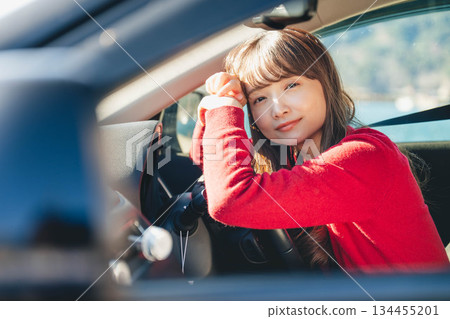 A young long-haired woman driving a car on a sunny day A young long-haired woman driving a car on a sunny day 134455201