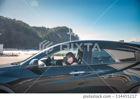 在陽光明媚的日子裡，一位留著長髮的年輕女子開車。 134455217