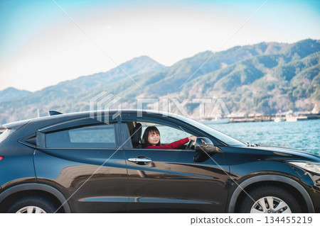 在陽光明媚的日子裡,一位留著長髮的年輕女子開車。 在陽光明媚的日子裡,一位留著長髮的年輕女子開車。 134455219