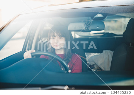 A young long-haired woman driving a car on a sunny day A young long-haired woman driving a car on a sunny day 134455220