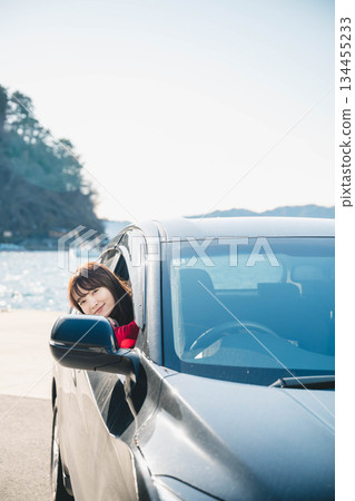 A young long-haired woman driving a car on a sunny day 134455233