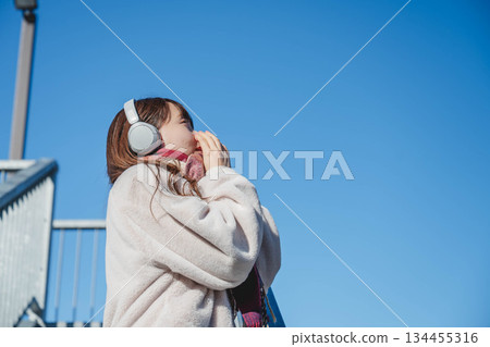 年輕女子坐在階梯上，仰望著天空。 134455316