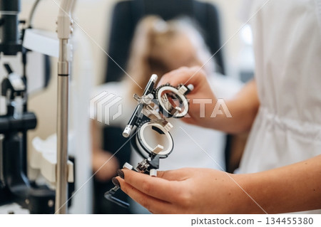Close up view of female doctor's hands that are holding ophthalmologist glasses Close up view of female doctor's hands that are holding ophthalmologist glasses 134455380